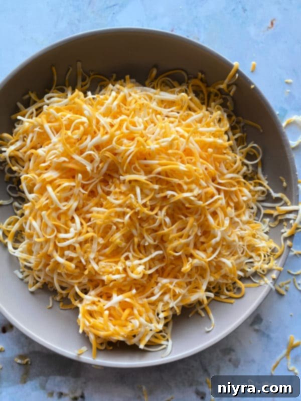 A block of cheese and a grater on a wooden cutting board, ready for grating.