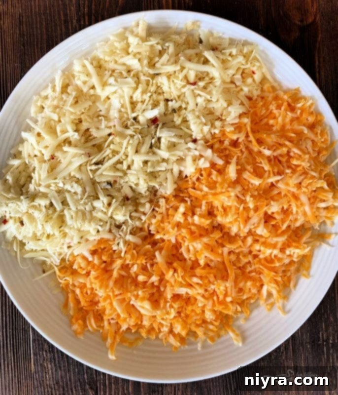 Freshly grated cheese in a bowl, with a grater and block of cheese in the background.