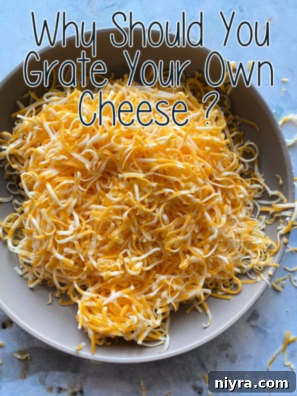 A bowl of freshly grated cheese with a grater in the background.