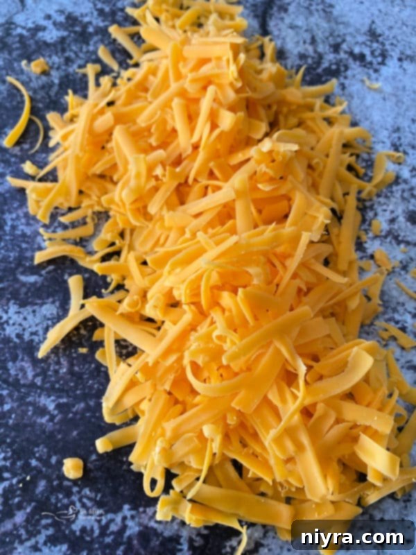 Close-up of a hand grating a block of cheese, highlighting the fresh shreds.