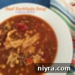 Ultimate Beef Enchilada Soup 2 Close-up of a bowl of Beef Enchilada Soup with cheese, cilantro, and tortilla strips.