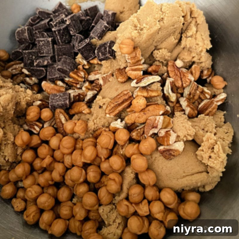 Cookie dough being mixed with caramel bits, chocolate chunks, and pecans.