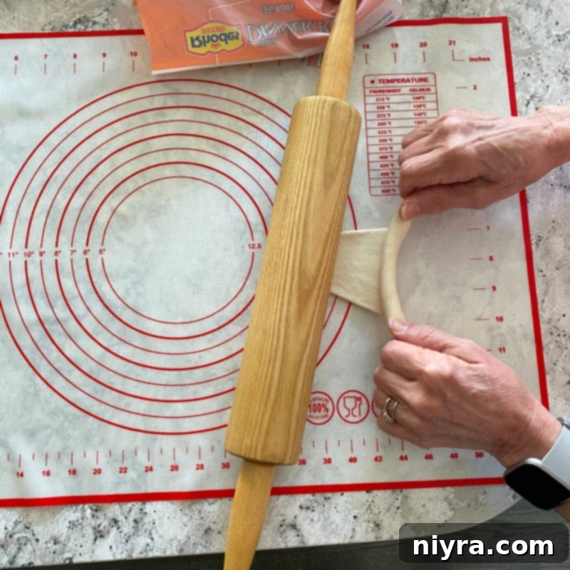 Tugging dough outward while rolling to stretch it