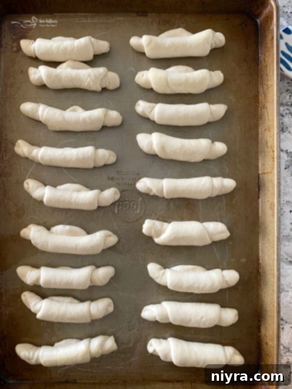 Arranging rolled poppyseed dough on a baking sheet, seam side down