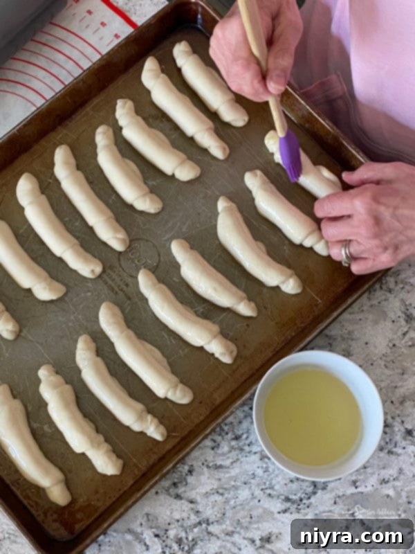 Brushing poppyseed rolls gently with vegetable oil