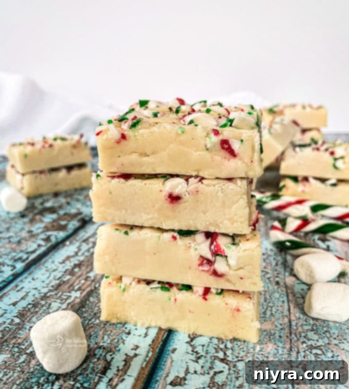 Close-up of freshly cut White Chocolate Peppermint Fudge squares adorned with crushed candy canes.