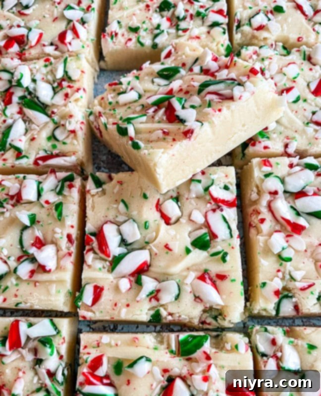 Overhead shot of freshly prepared White Chocolate Peppermint Fudge cooling in a foil-lined baking dish, topped with crushed candy canes.