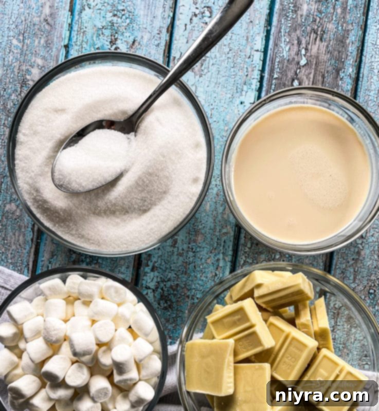 Ingredients for White Chocolate Peppermint Fudge laid out on a table: sugar, evaporated milk, butter, white chocolate chips, miniature marshmallows, vanilla extract, peppermint extract, and crushed candy canes.