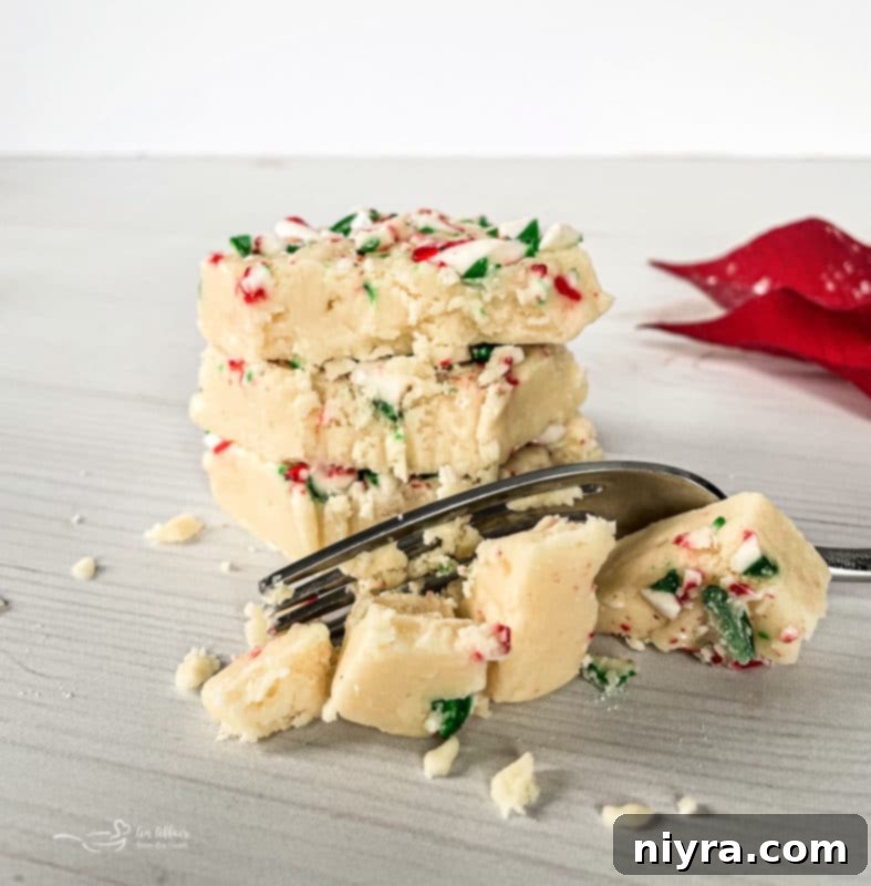 Close-up of stacked White Chocolate Peppermint Fudge pieces, showing the creamy texture and crushed candy cane topping.