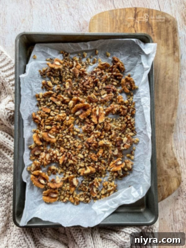 Decadent Bittersweet Chocolate Bourbon Balls 5 Step-by-step image showing walnuts being toasted on a baking sheet, part of the process for making Chocolate Bourbon Balls.