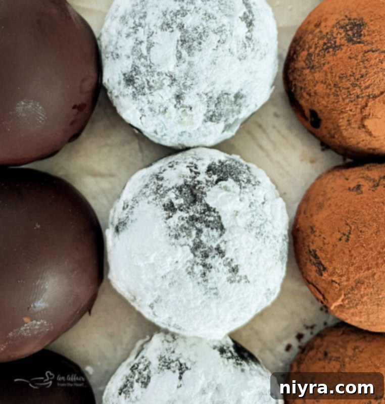 Decadent Bittersweet Chocolate Bourbon Balls 9 An artfully arranged stack of Bittersweet Chocolate Bourbon Balls, some dusted with cocoa, others with powdered sugar, creating an inviting display.