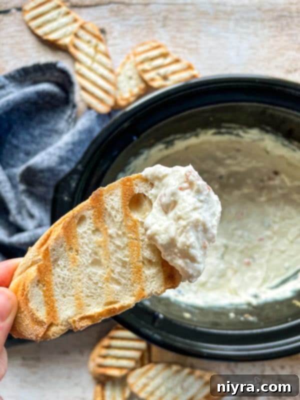 Close-up of Slow Cooker Crab Dip with toasted bread and a fork, highlighting its creamy texture.