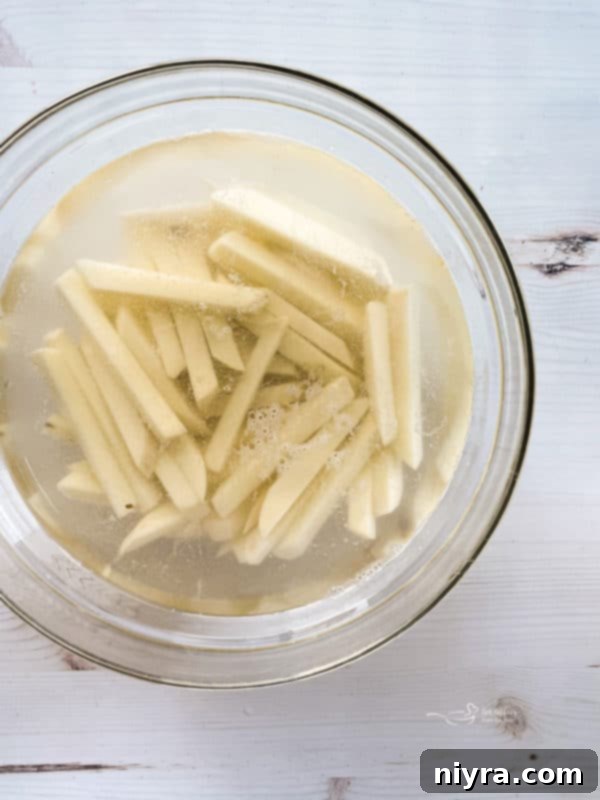 Perfectly Crispy Homemade French Fries 10 Bowl of peeled and cut fries in bowl of cold water, emphasizing the importance of soaking