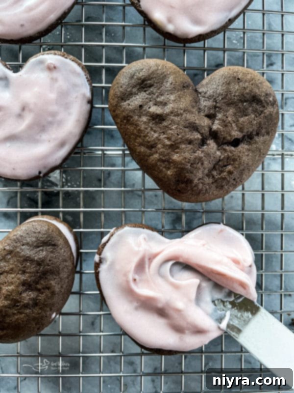 Piping strawberry cream cheese filling onto one half of a chocolate whoopie pie