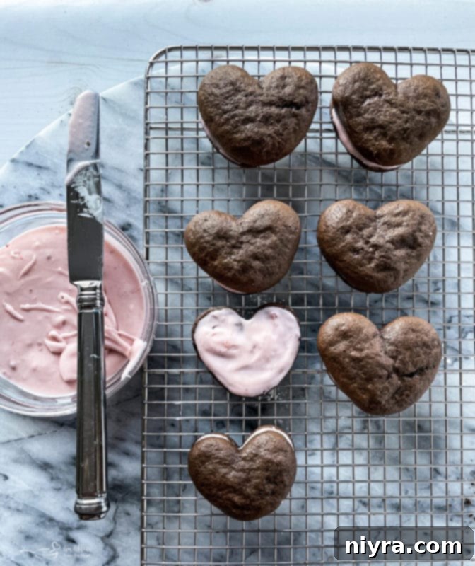 Placing another chocolate whoopie pie half on top of the filling to assemble