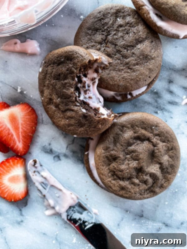 Close up of a Chocolate Strawberry Whoopie Pie with a bite taken out, showing the pink filling