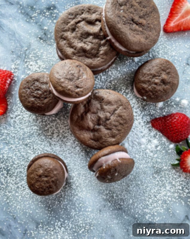 Chocolate Strawberry Whoopie Pies with powdered sugar and fresh strawberries scattered around