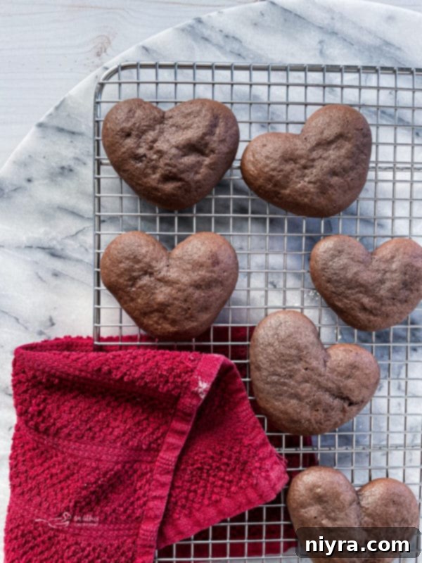 Baked heart-shaped chocolate whoopie pie halves on a cooling rack