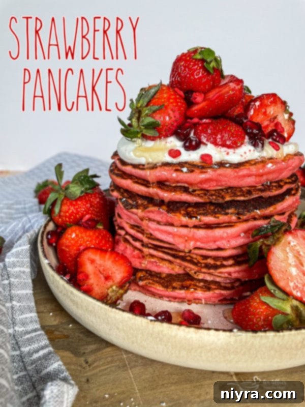 Dreamy Strawberry Pancakes 17 A stack of beautifully plated strawberry pancakes, adorned with fresh strawberries and a dusting of powdered sugar, captured in a warm, inviting light.