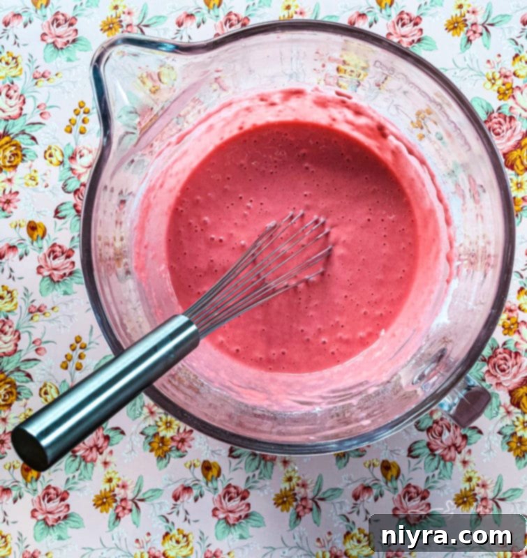 Dreamy Strawberry Pancakes 7 Wet ingredients (eggs, milk, and vegetable oil) being whisked together in a glass bowl, forming a smooth liquid mixture.