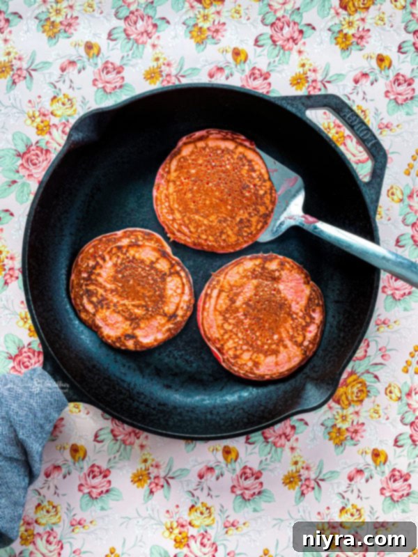 Dreamy Strawberry Pancakes 8 Pancake batter being poured from a ladle onto a hot, greased griddle, forming perfect circular pancakes.