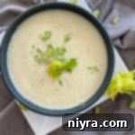 Close up of Cream of celery soup in a blue bowl with gray background