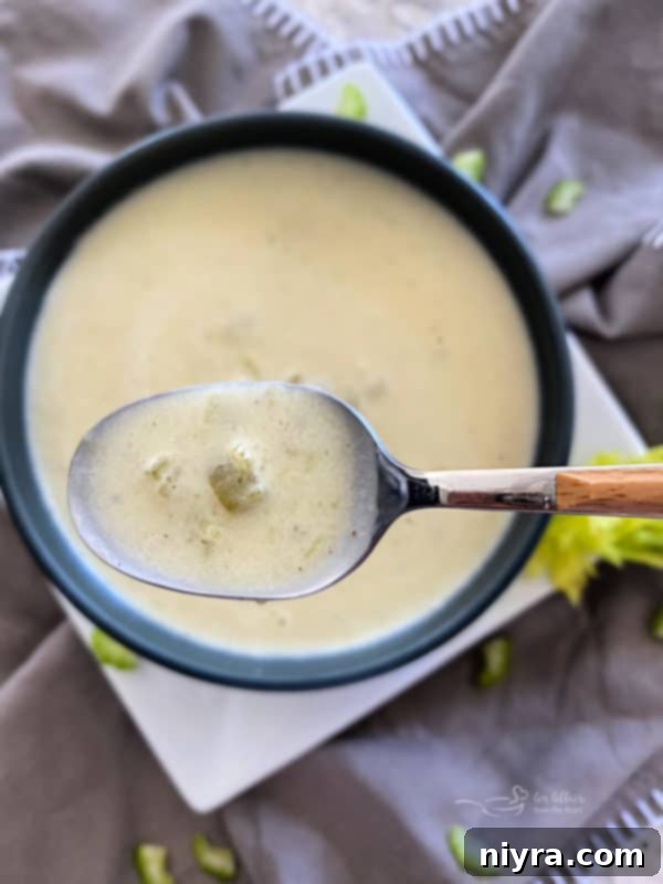Close up of a spoon scooping Instant Pot Cream of Celery Soup from a blue bowl