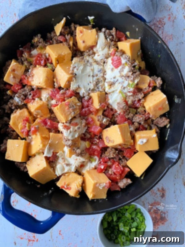 Ultimate Sausage Cheese Dip 5 Cubed Velveeta and cream cheese added to cooked sausage and Rotel in a skillet