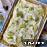 Delicious Key Lime Slab Pie, topped with whipped cream and a lime slice.