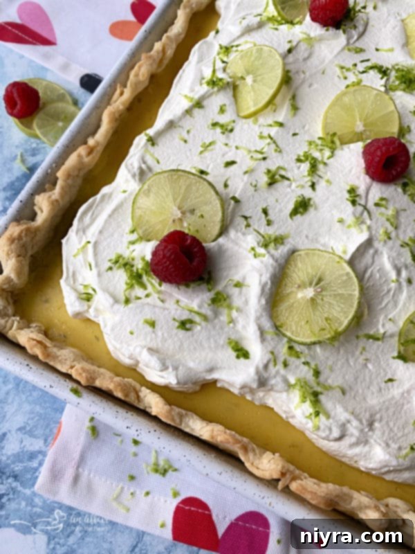 An overhead view of a slice of Key Lime Slab Pie, highlighting the thick layer of custard and whipped cream on a flaky crust.