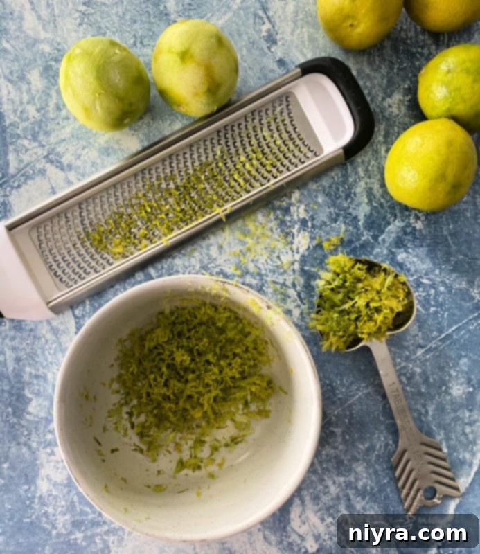 A close-up of a Key Lime, showing its small size and yellowish-green skin, contrasting with a larger, darker green Persian lime.