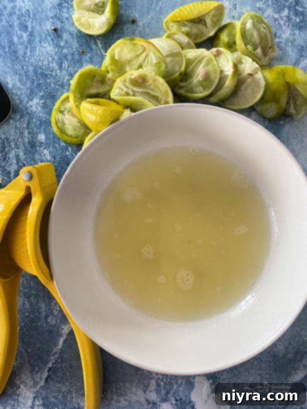 A glass measuring cup filled with freshly squeezed Key Lime juice, alongside whole Key Limes and a zester.