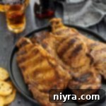 Jack and Coke steaks on a plate with a shot of Jack and a bottle of Coke in the background.