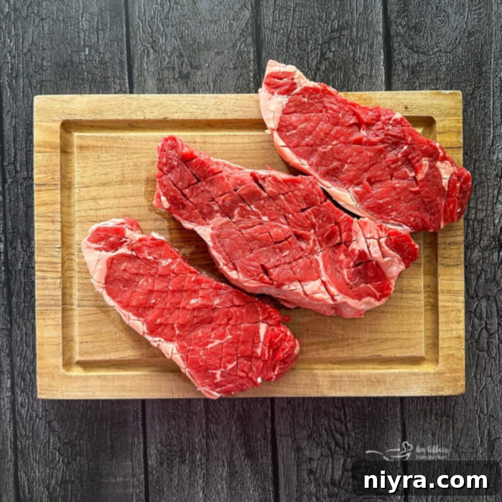 Scoring a New York strip steak with a sharp knife.