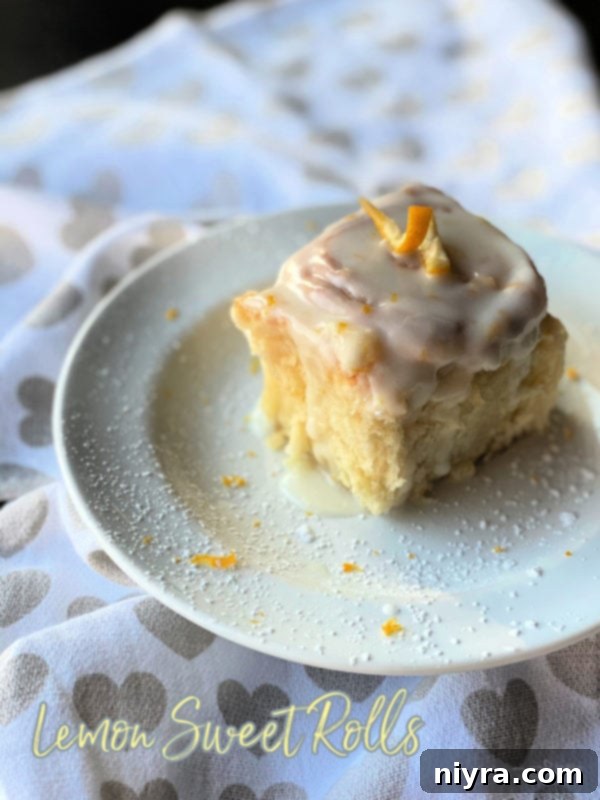 Front view of a stack of glazed lemon sweet rolls on a white plate, ready to be served