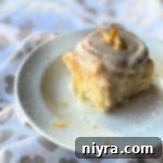A single lemon sweet roll with glaze, presented on a white plate