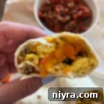Close up of the inside of a breakfast burrito showing its rich, colorful filling.