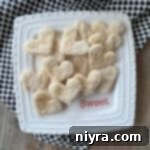 Heart-shaped pie crust cookies on a white, square dish.
