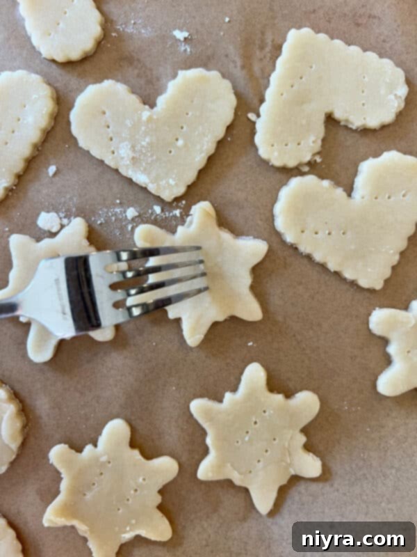 Heart-shaped pie crust cookies cut out and placed on a parchment-lined baking sheet.