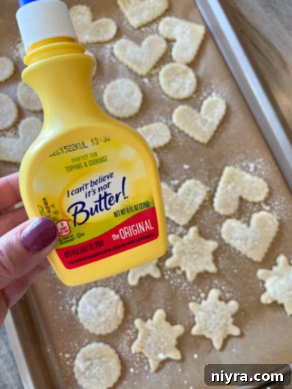 Poking holes into raw pie crust cookies with a fork on a baking sheet.