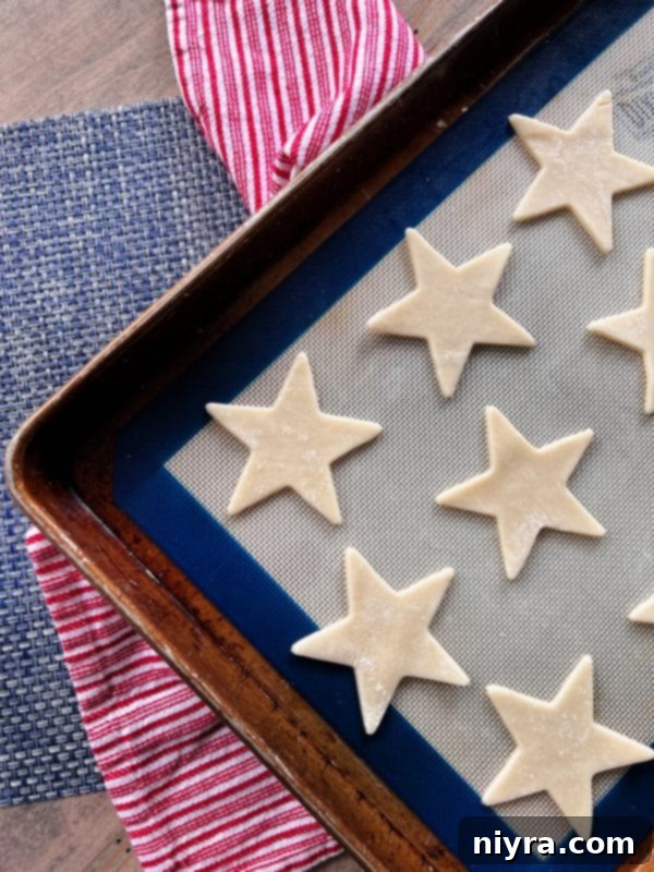 Whipped cream being added on top of a berry layer in a white bowl.