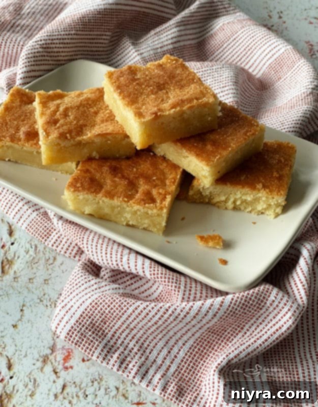 Dutch Almond Letter Bars 3 A stack of golden brown Dutch Letter bars, dusted lightly, arranged on a white plate, ready to be enjoyed.