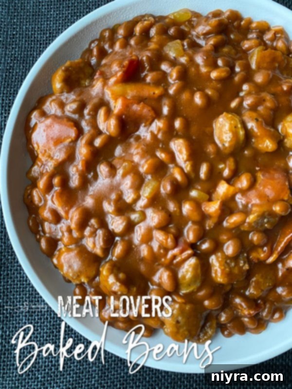 A large serving of Meat Lovers Baked Beans with a wooden spoon in a rustic bowl