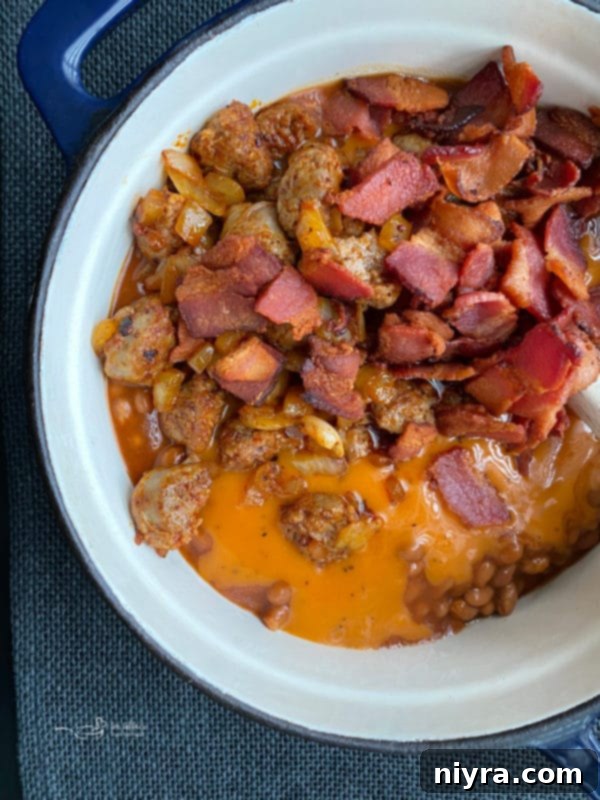 Close-up of Meat Lovers Baked Beans simmering in a cast iron Dutch oven on the stovetop