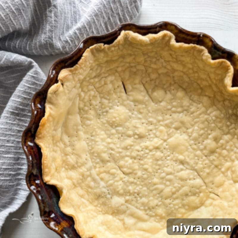 Pie dough carefully placed into a ceramic pie plate, with the edges being trimmed to create a perfect crust for baking.