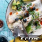 Two enchiladas on plate with fork and knife