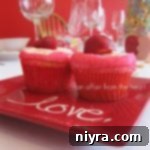 Side view of 2 Strawberry daiquiri cupcakes on a red plate that ahs the word love on it