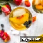 Overhead of rose sangria topped with slices of peach and blueberries.