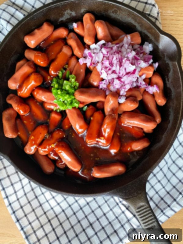 Adding sauce, onion, and pepper to little smokies in a skillet