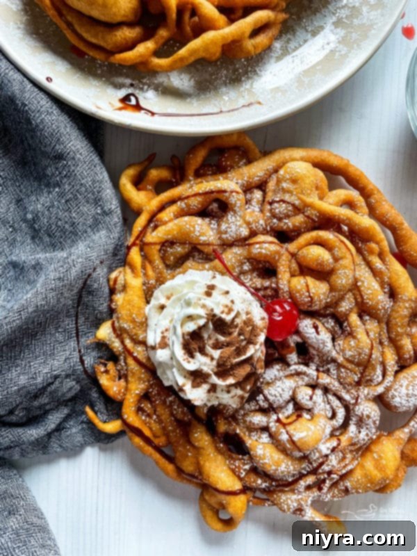 A close-up of a homemade funnel cake artfully garnished with a swirl of whipped cream, a bright cherry, and a drizzle of rich chocolate sauce.